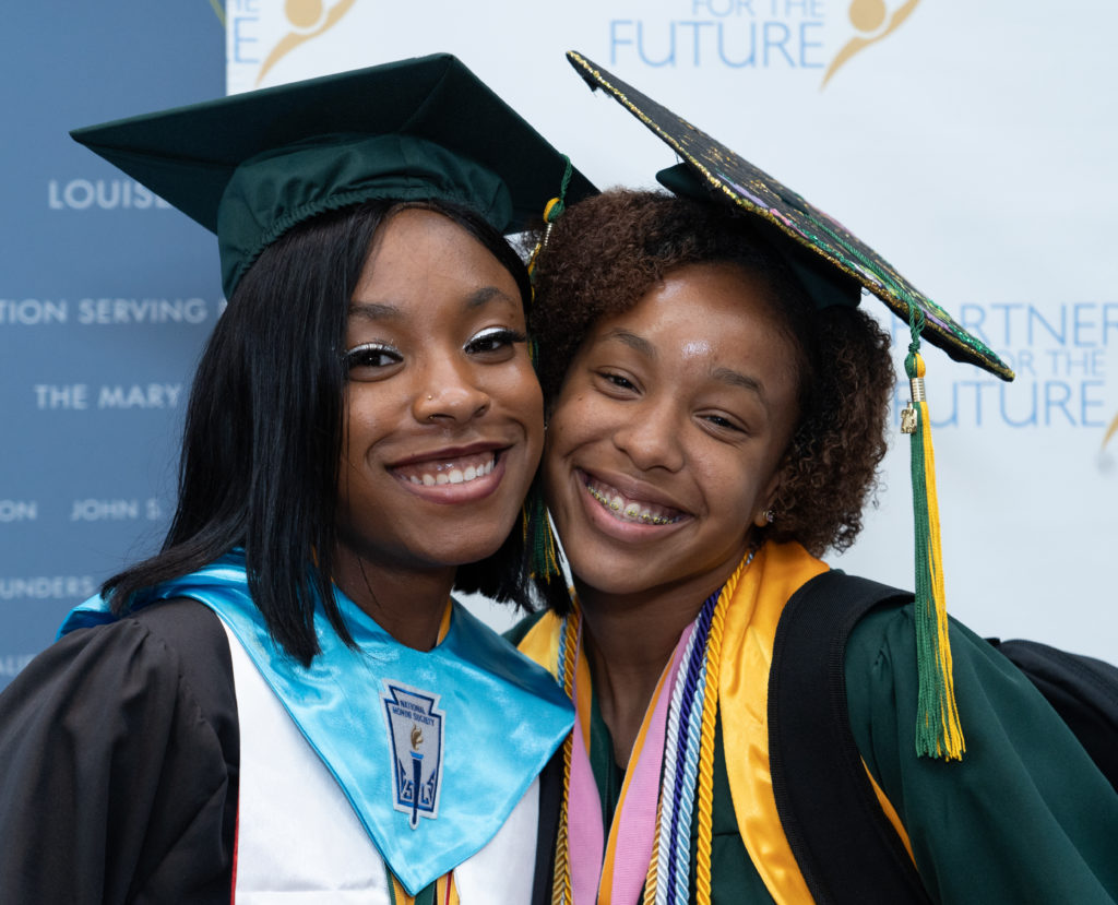 2 graduates smiling at camera