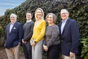 Photo of the 5 consultants of The Monument Group, all standing outside.